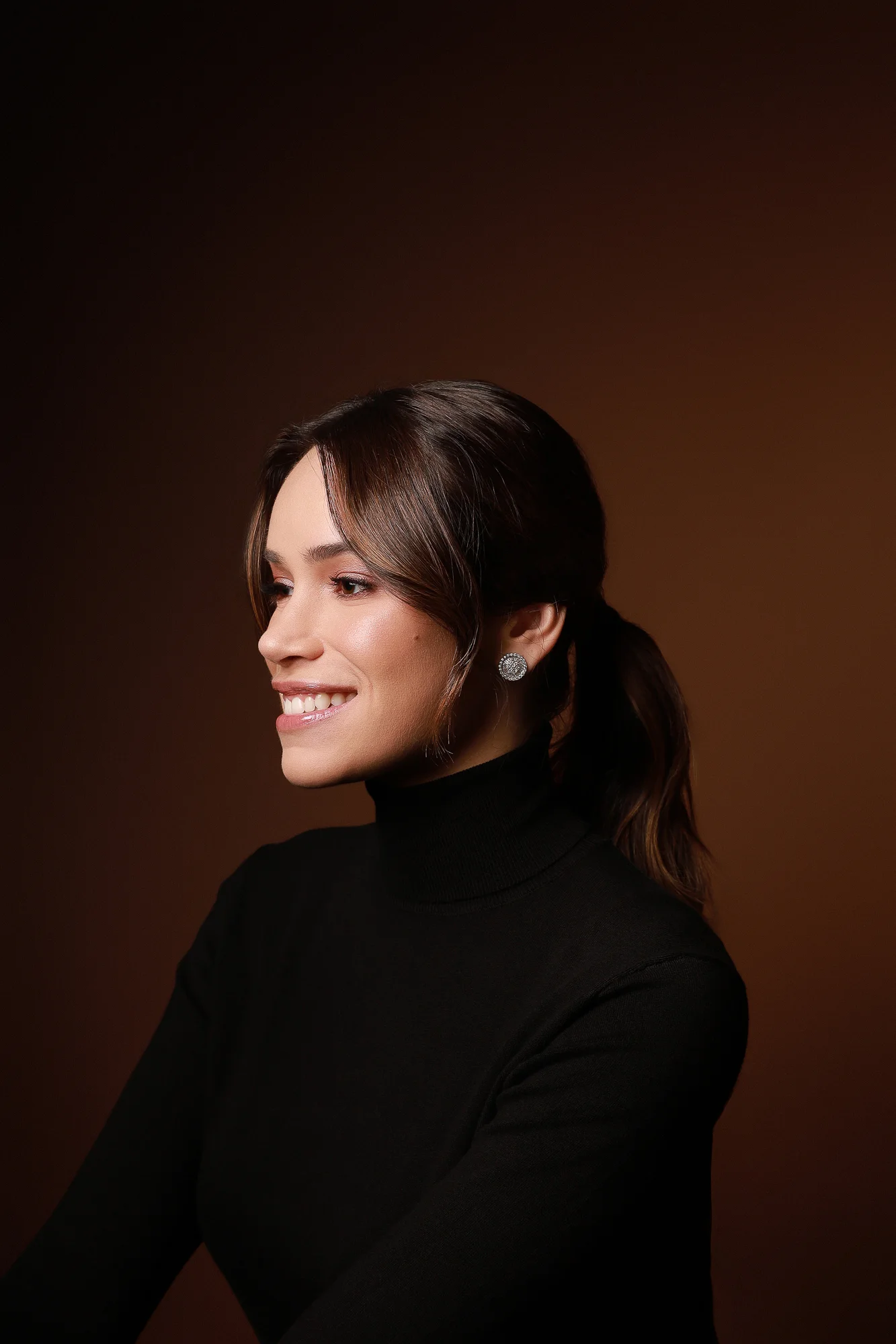 Dra. Mariana Sathler de perfil, sorrindo, usando blusa preta.
